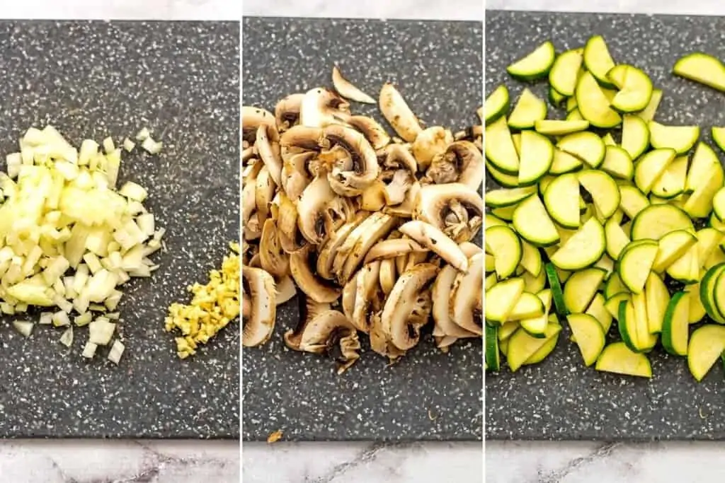 Cutting board with chopped onion, garlic, mushrooms and zucchini.