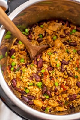 Instant pot filled with Cajun chicken and rice with wooden spoon.