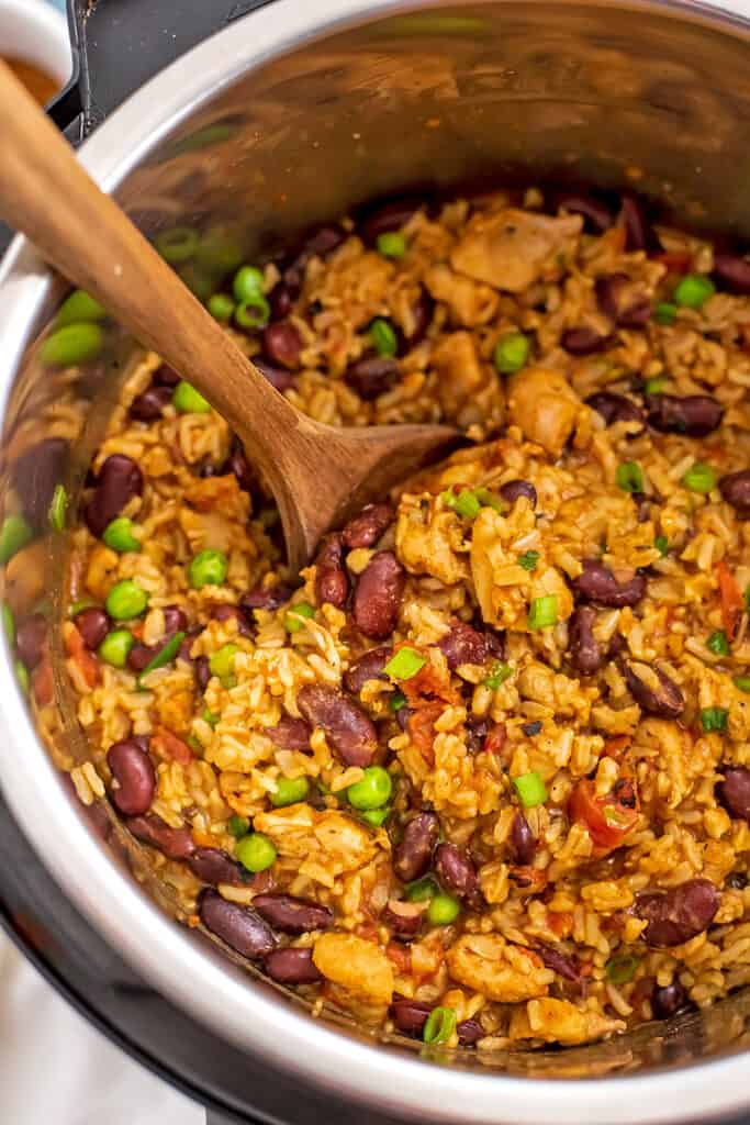 Instant pot filled with Cajun chicken and rice with wooden spoon.