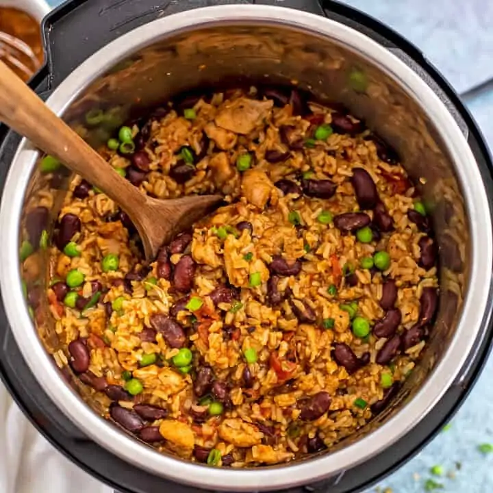 Wooden spoon in instant pot filled with cajun chicken and rice.