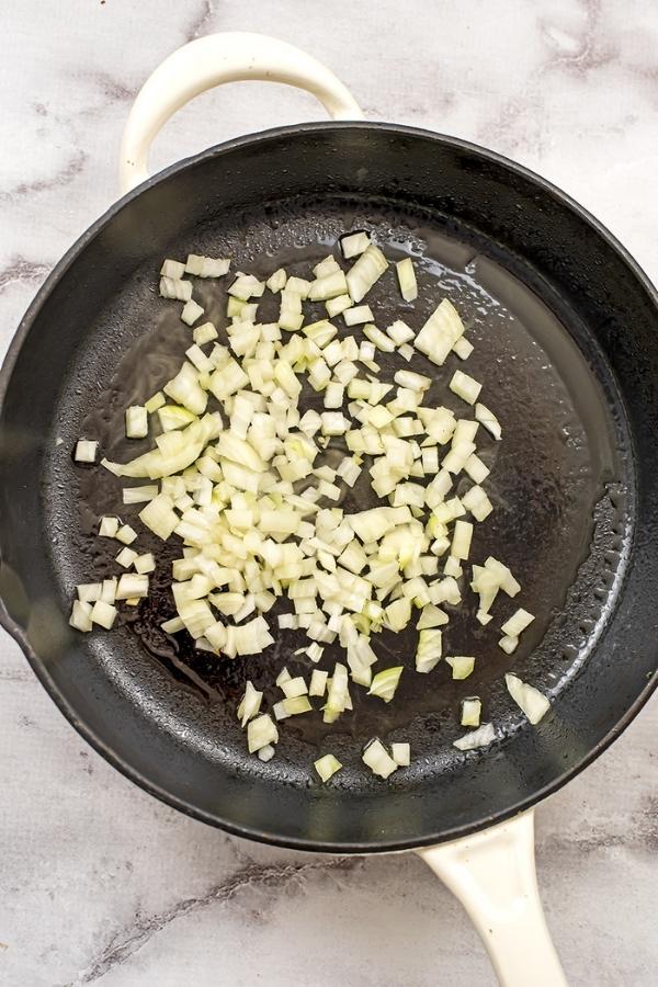 Chopped onions in a cast iron skillet.