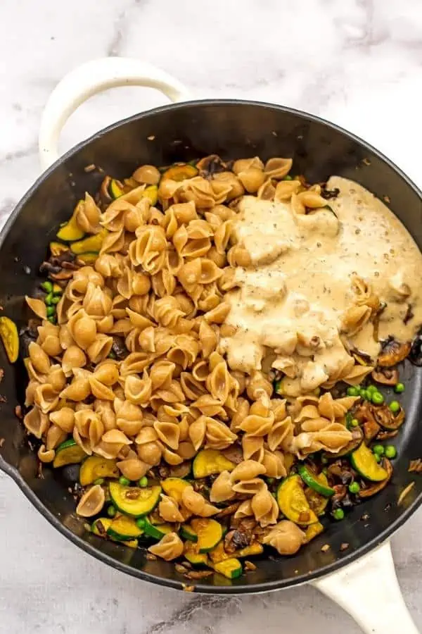 Lemon tahini sauce, pasta and frozen peas added to skillet with veggies.