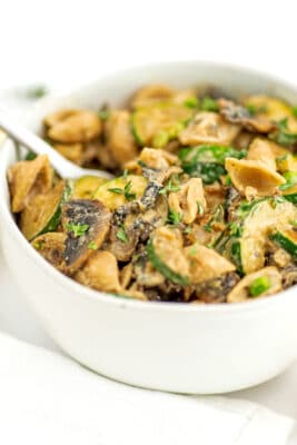 Fork resting in bowl filled with zucchini mushroom pasta.
