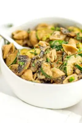 Fork resting in bowl filled with zucchini mushroom pasta.