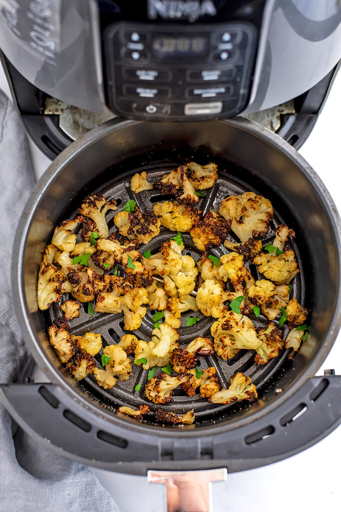 Air fryer basket filled with roasted cauliflower cooked from frozen. 
