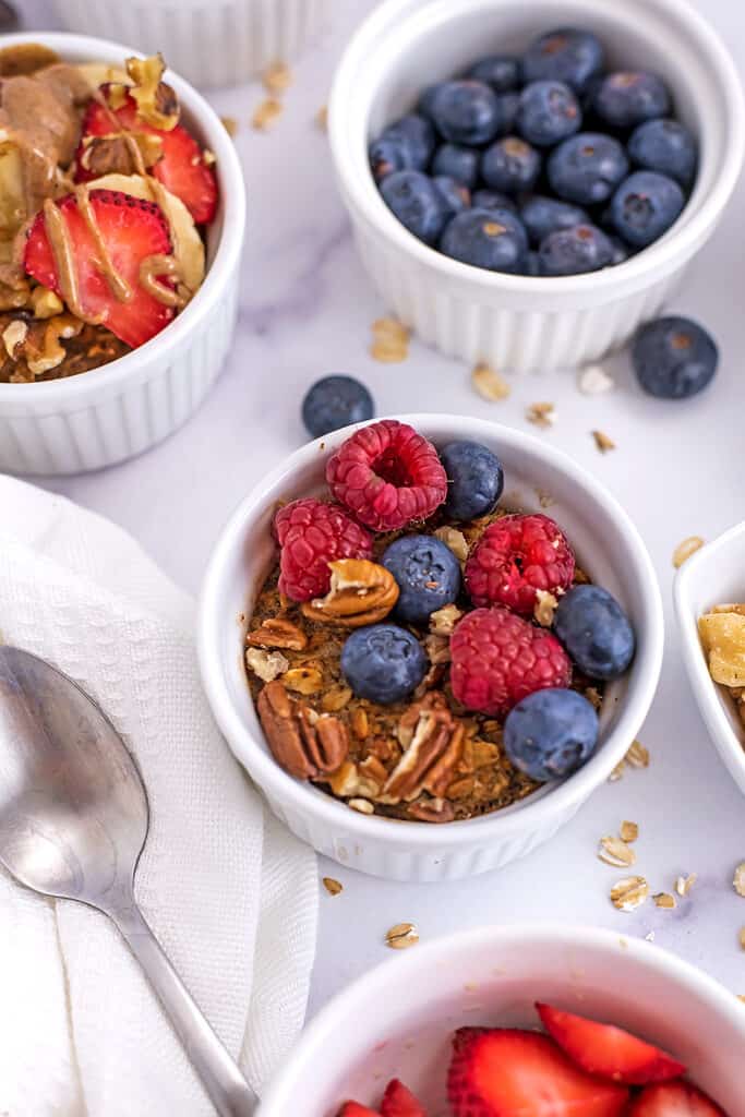 Blueberries and raspberries on top of air fryer baked oatmeal in white ramekin.