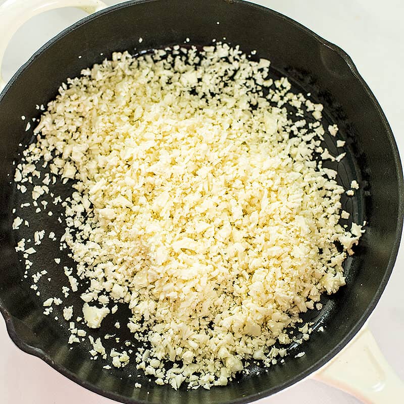 raw cauliflower rice in a cast iron skillet.