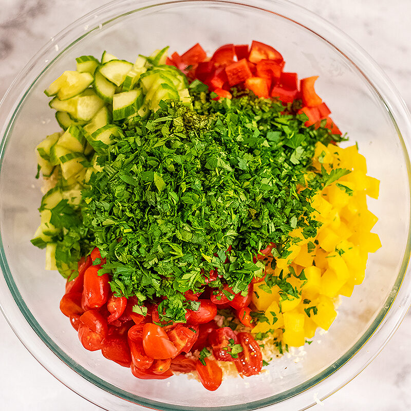 finely chopped veggies like pepper, cucumbers and tomatoes added to glass bowl.