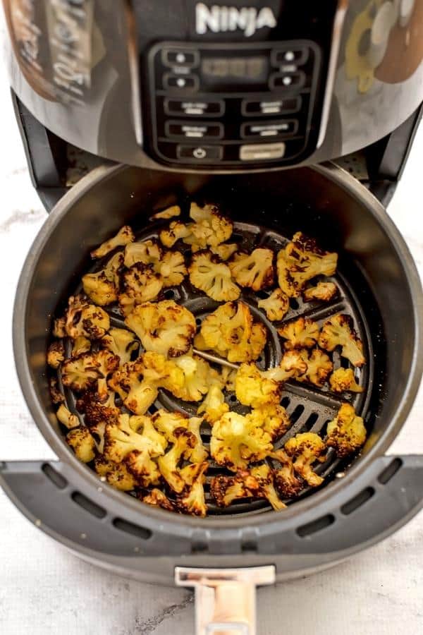 Roasted cauliflower in air fryer basket after being cooked from frozen.