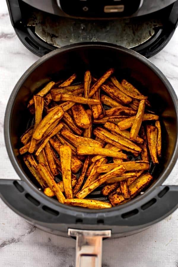 Roasted parsnips in air fryer basket after cooking.