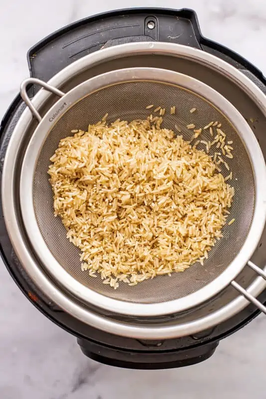 Brown jasmine rice in a mesh strainer over the instant pot.