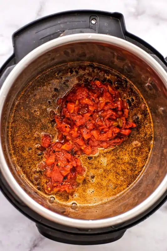 Diced tomatoes added to instant pot with rice and beans.