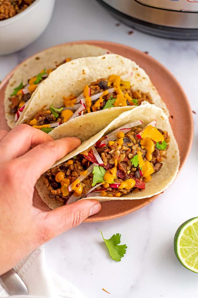 Hand holding a taco filled with instant pot Mexican rice and beans.