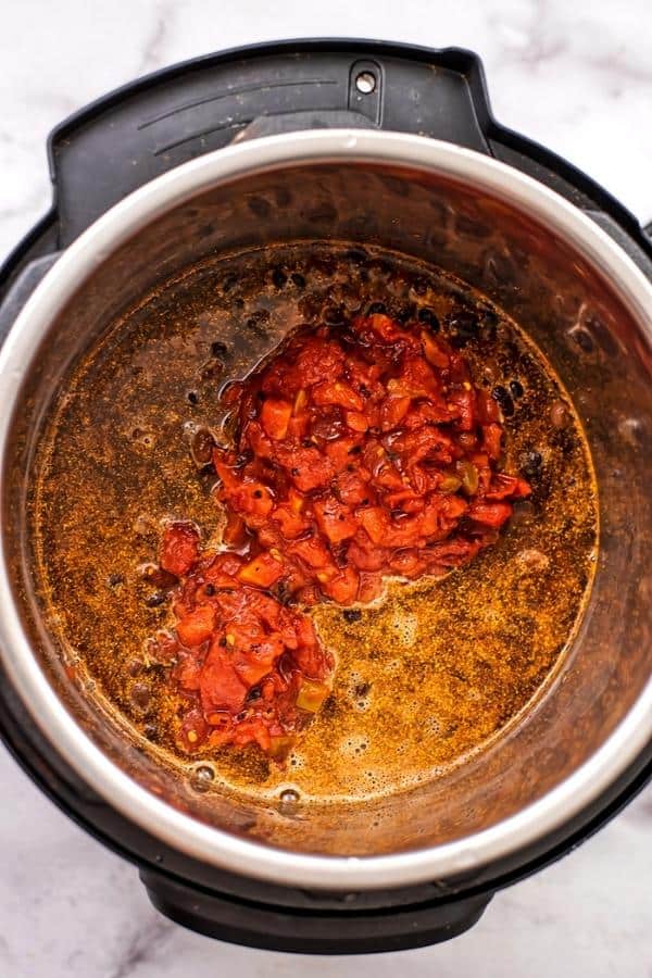 Drained diced tomatoes added to instant pot with rice and beans.