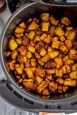 Cubed potatoes in air fryer basket after cooking.