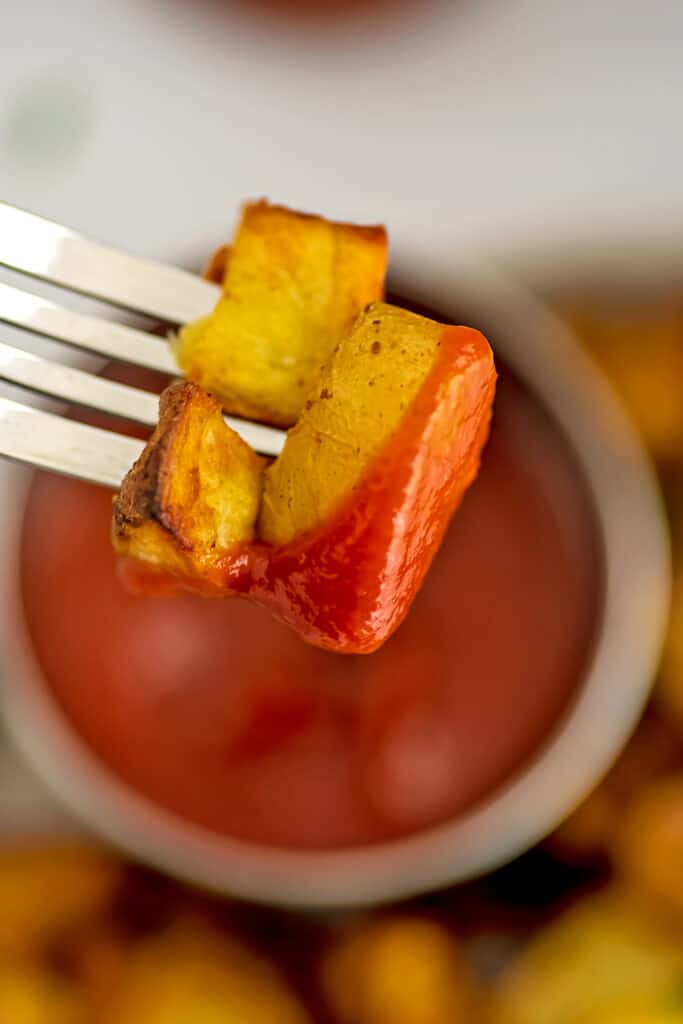 Air fryer diced potatoes on a fork dipped in ketchup.