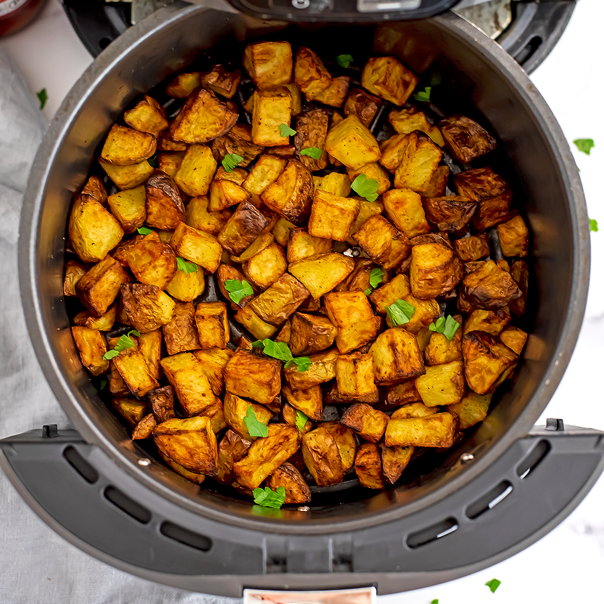 Cooked diced potatoes in air fryer basket.