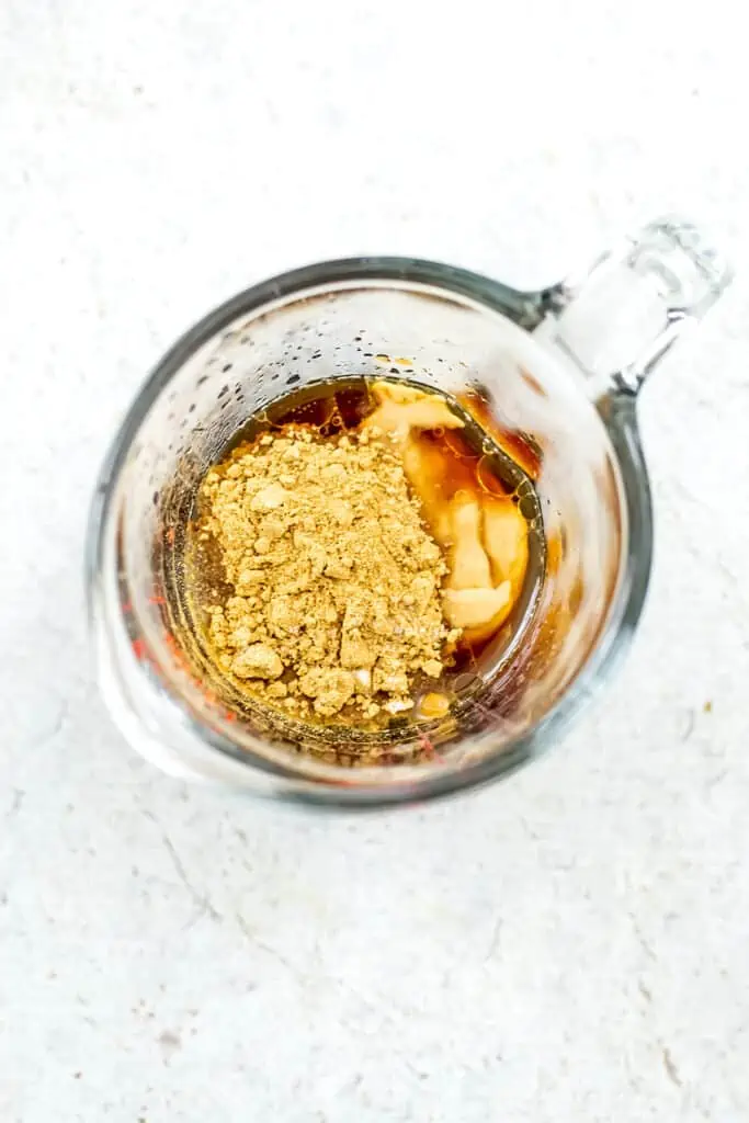 ingredients to make sesame ginger dressing in measuring cup before stirring. 