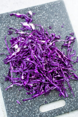 Shredded red cabbage on cutting board.