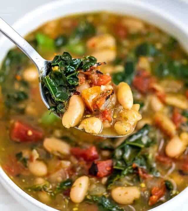 Spoonful of spicy white bean soup over the bowl.