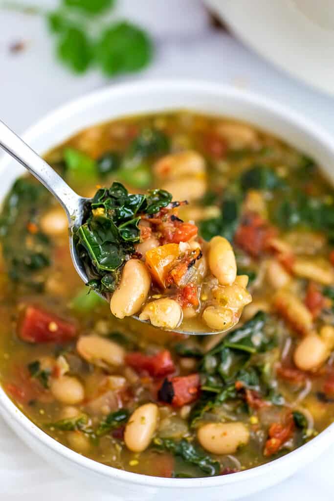 Spoonful of spicy white bean soup over the bowl.