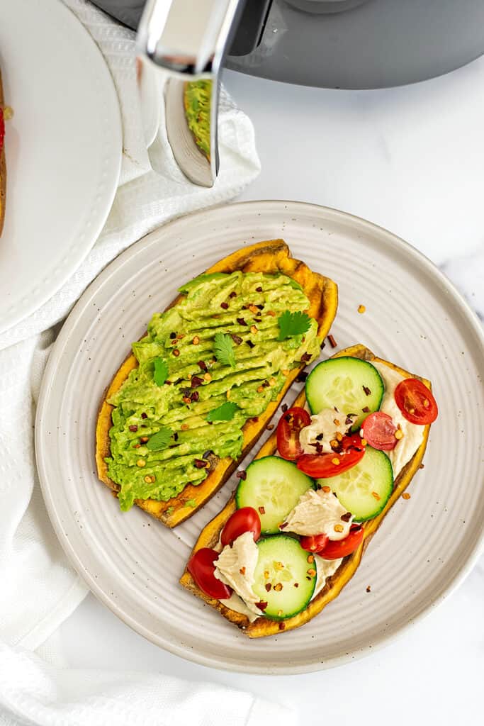 Avocado sweet potato toast and veggies and hummus sweet potato toast on plate.