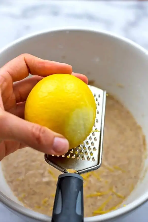 Almond flour blackberry muffins batter getting lemon zest using zesting microplane.