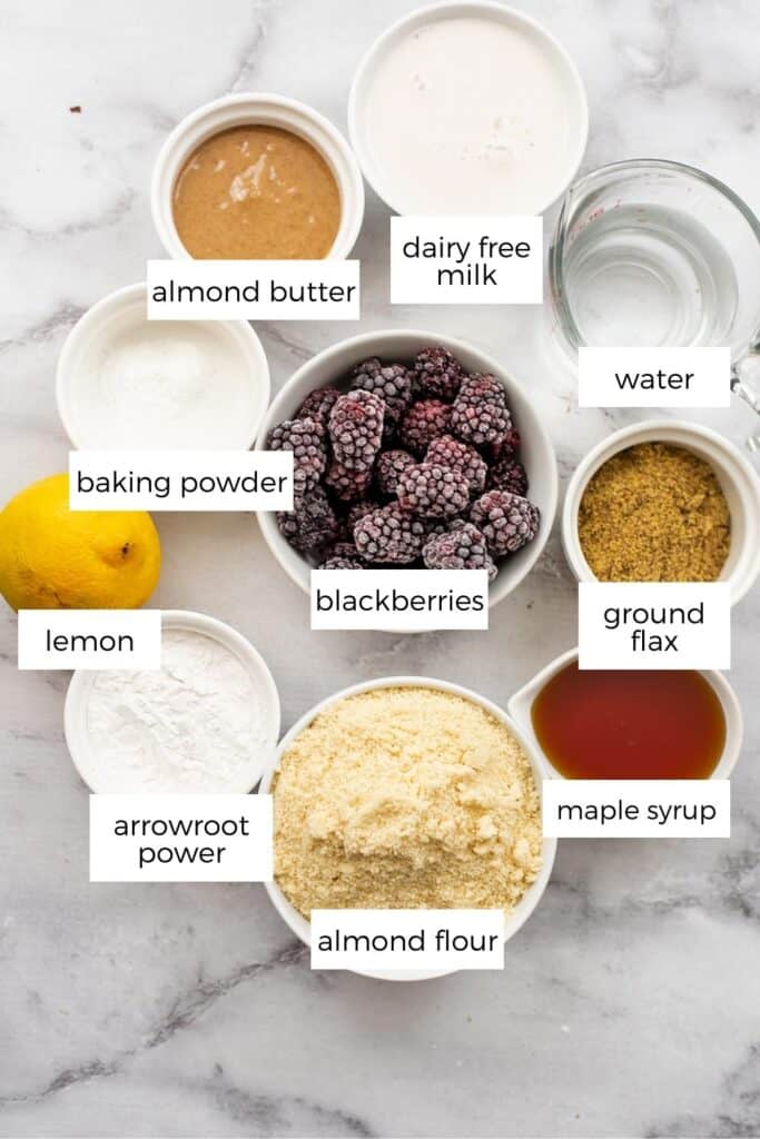 Ingredients to make vegan blackberry muffins in white ramekins and bowls.