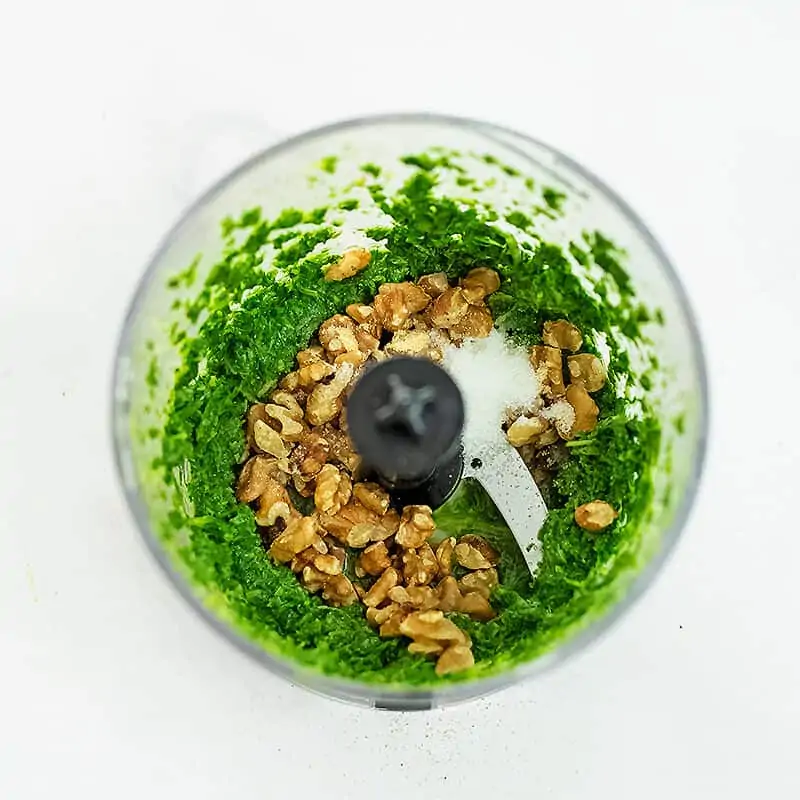 Walnuts, salt and garlic powder added to food processor with basil.
