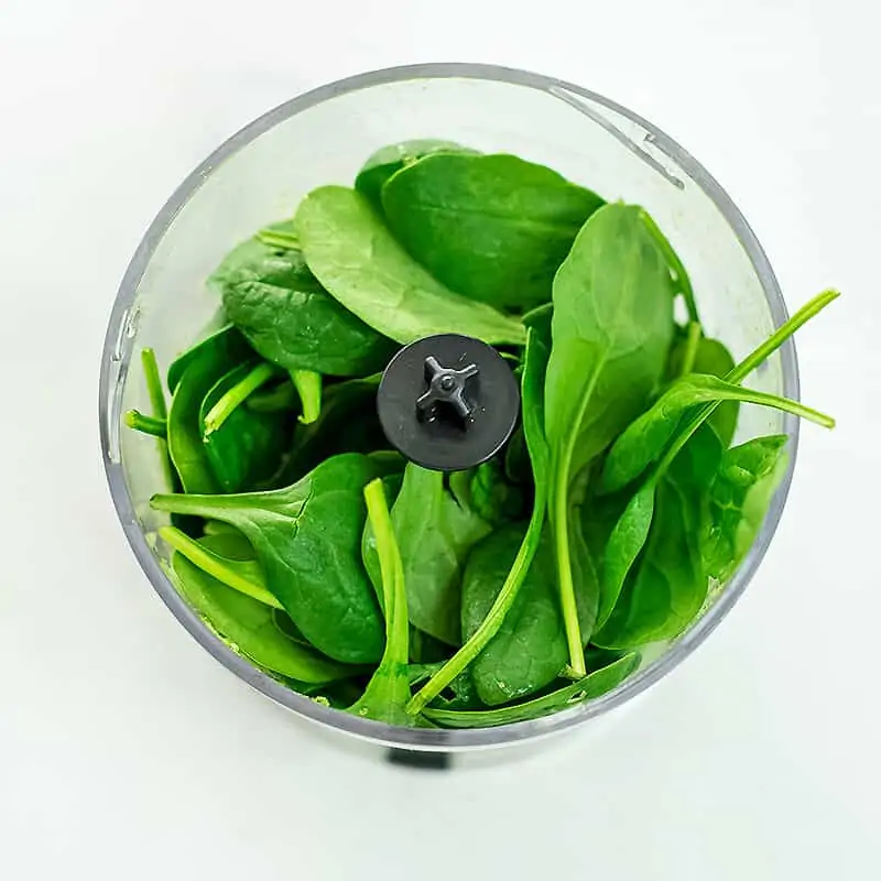 Baby spinach added to food processor with basil.