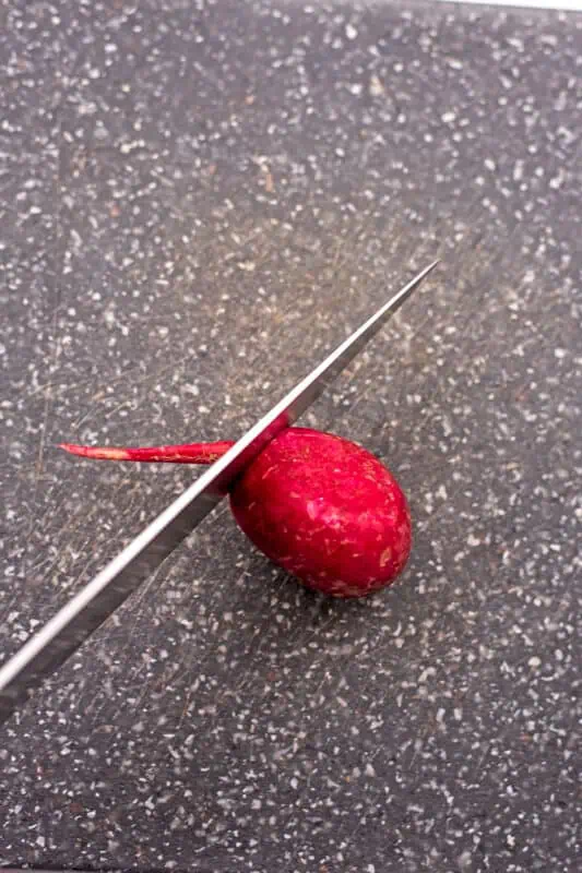 Knife cutting the end off a radish.