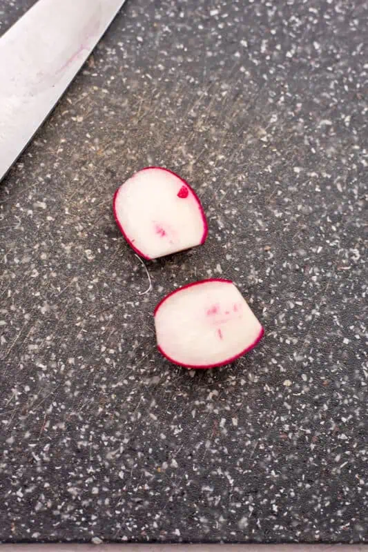 Radish cut in half on a cutting board.