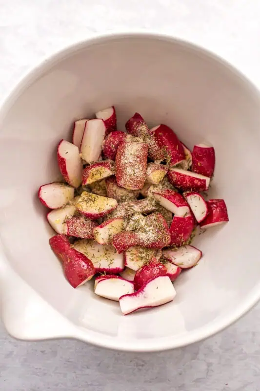 Radish halves in a large with bowl with spices.