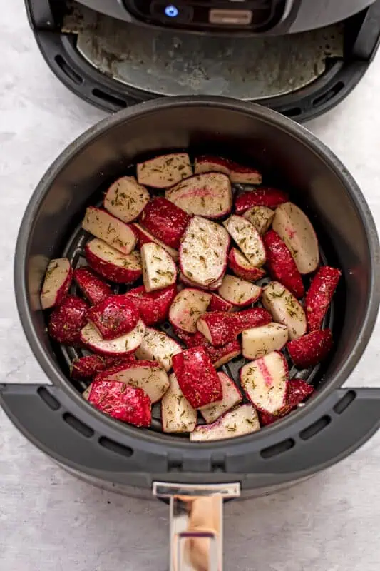 Radishes in air fryer basket before cooking.