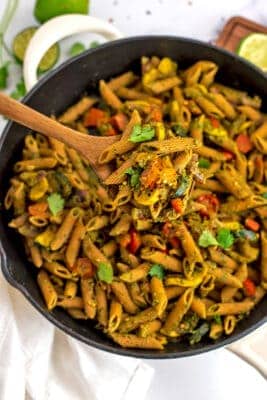 Spoon scooping out a serving of chimichurri pasta from a skillet.