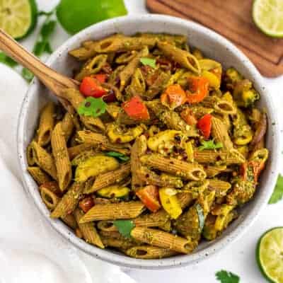 Chimichurri pasta in a white bowl with a wooden spoon.