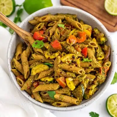 Chimichurri pasta in a white bowl with a wooden spoon.