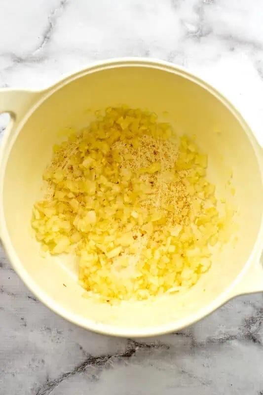 White onions cooking in a white pot.