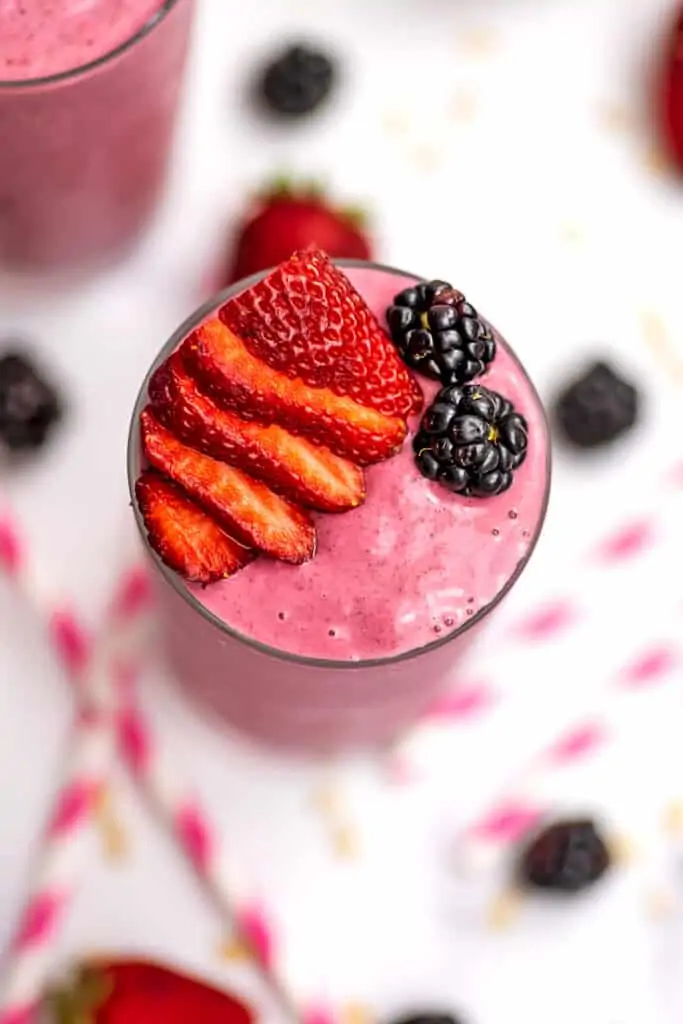 Strawberry blackberry banana smoothie in a glass with sliced strawberries and blackberries on top.
