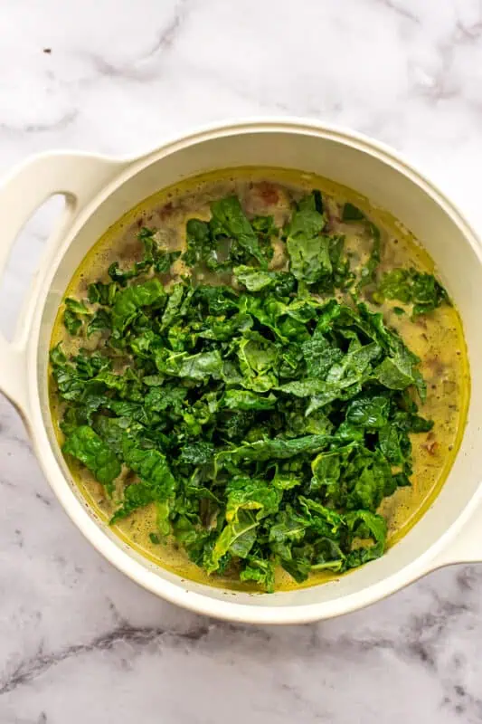 Fresh kale added to pot of soup.