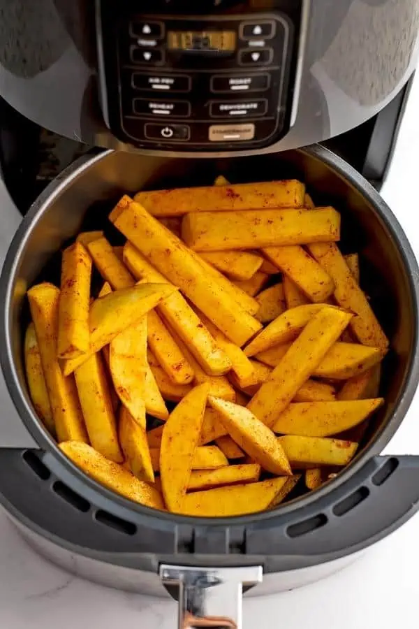 Rutabaga fries in the air fryer basket before cooking.