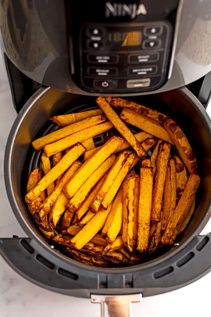 Air fryer rutabaga fries in air fryer basket after cooking.