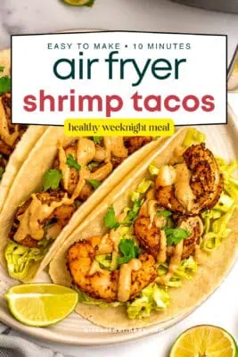 Shrimp tacos on a white plate with lime wedges on the plate.