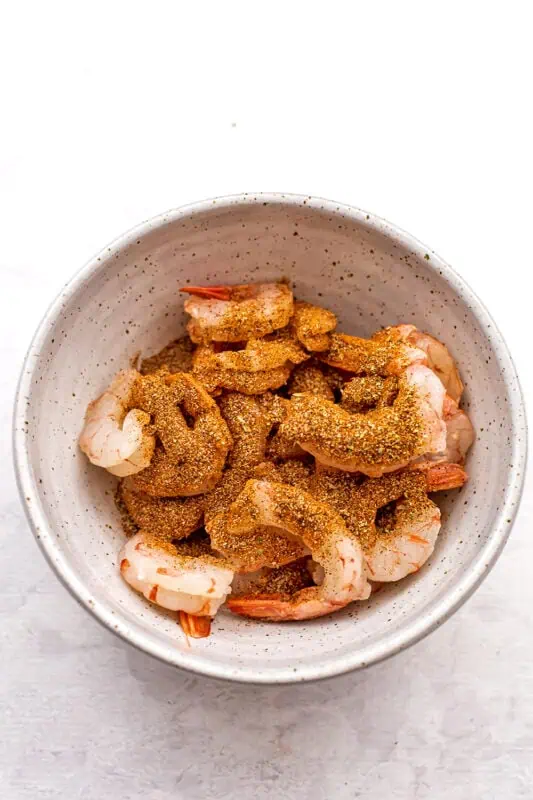 Shrimp in a bowl with spices on top.