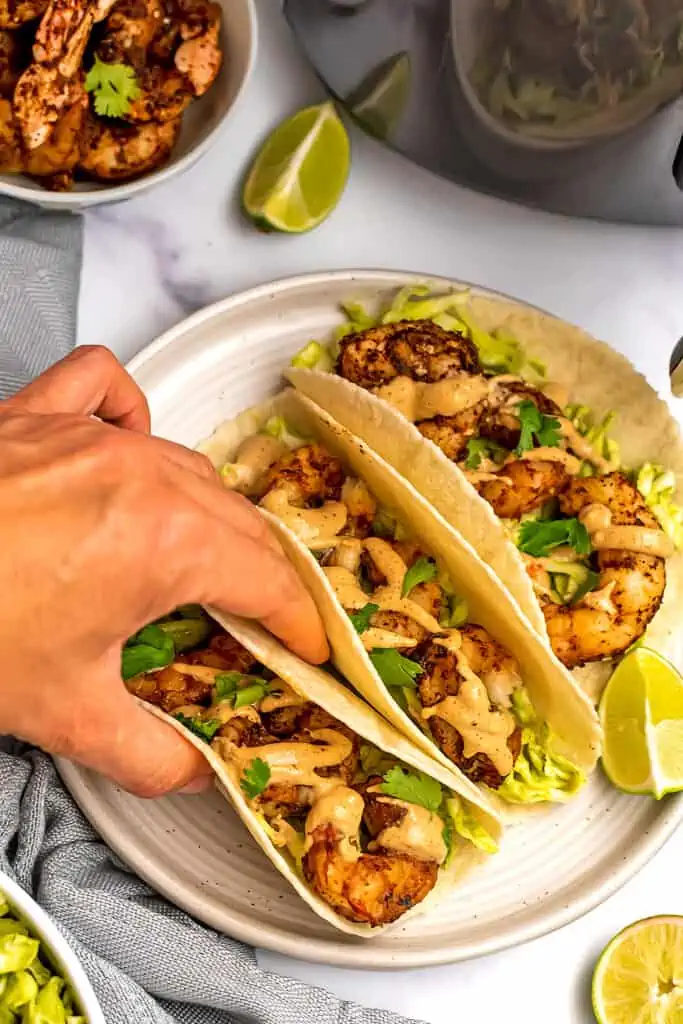 Hand holding a air fryer shrimp tacos.
