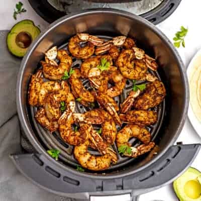 Taco seasoned shrimp in an air fryer basket.