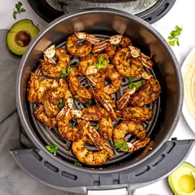Taco seasoned shrimp in an air fryer basket.