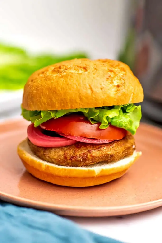 Air fryer frozen turkey burger with lettuce, tomato and pickled onions on burger.