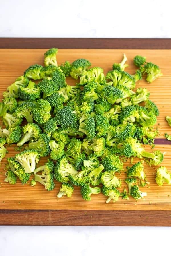 Broccoli florets cut into small pieces on cutting board.