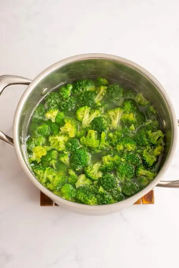 Broccoli florets added to boiling pasta water.